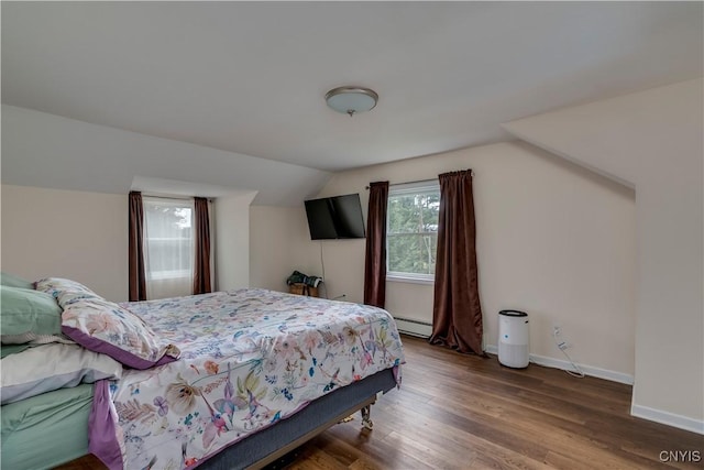 bedroom with baseboards, a baseboard heating unit, vaulted ceiling, and wood finished floors