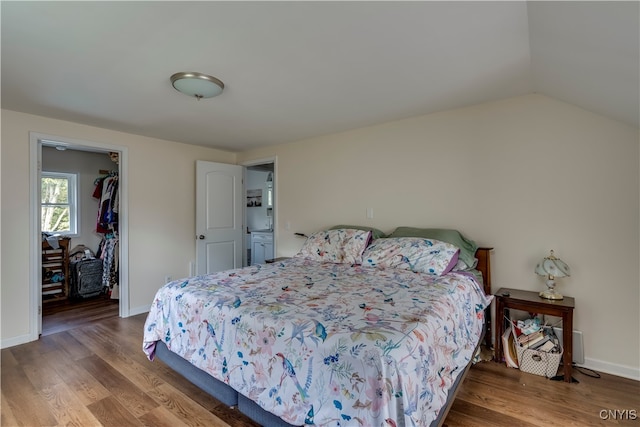 bedroom featuring wood-type flooring, lofted ceiling, a closet, and a walk in closet