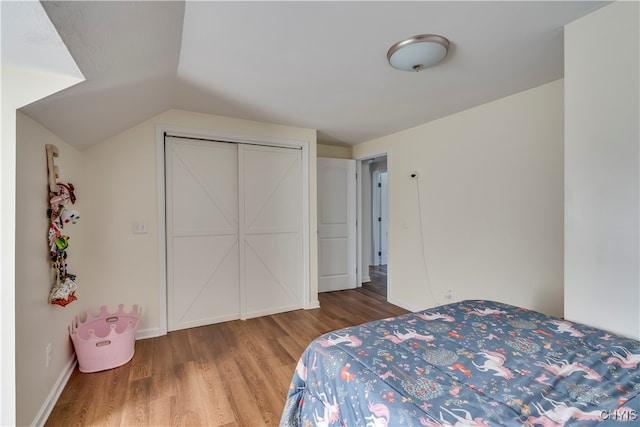 bedroom with vaulted ceiling, a closet, and hardwood / wood-style flooring