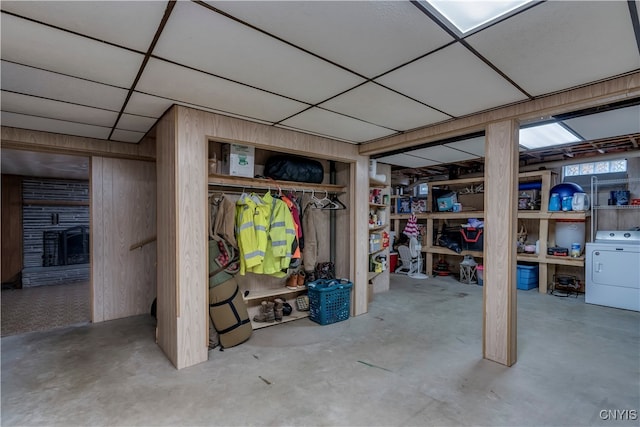 basement with wooden walls, washer / clothes dryer, a fireplace, and a paneled ceiling