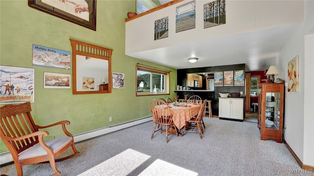 carpeted dining area featuring a baseboard radiator and a high ceiling