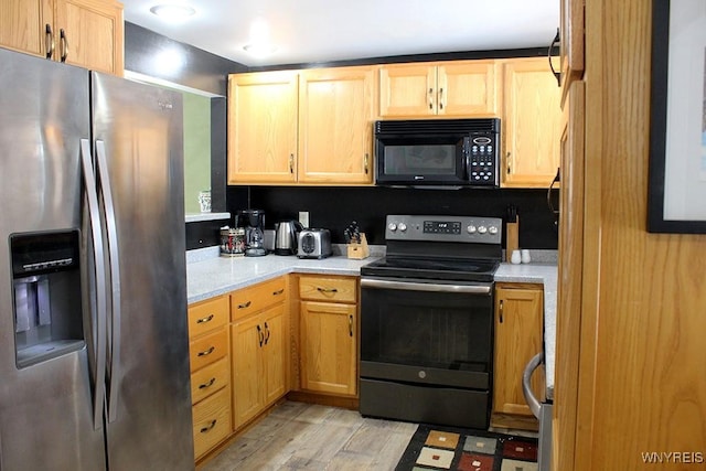 kitchen featuring stainless steel fridge with ice dispenser, range with electric stovetop, and light wood-type flooring