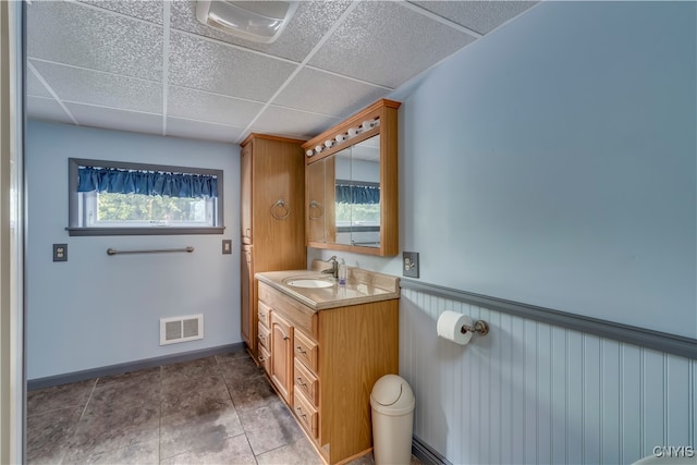 bathroom featuring a healthy amount of sunlight, a drop ceiling, vanity, and tile patterned floors