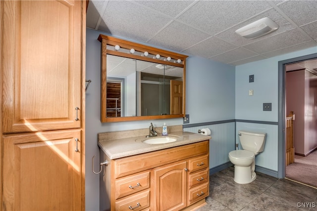 bathroom featuring a drop ceiling, vanity, and toilet