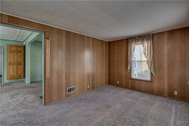 carpeted spare room with wood walls