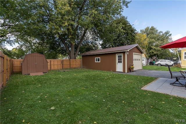 view of yard with a garage, a patio, and a storage unit