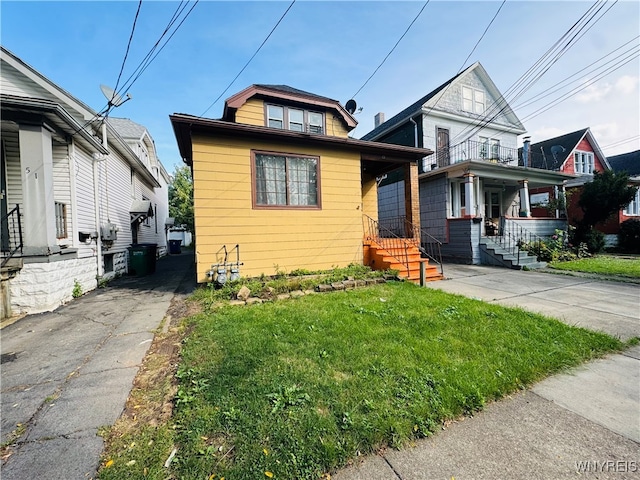 bungalow-style home featuring a balcony and a front lawn