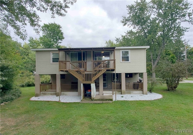 rear view of property with a wooden deck, a lawn, and a patio area