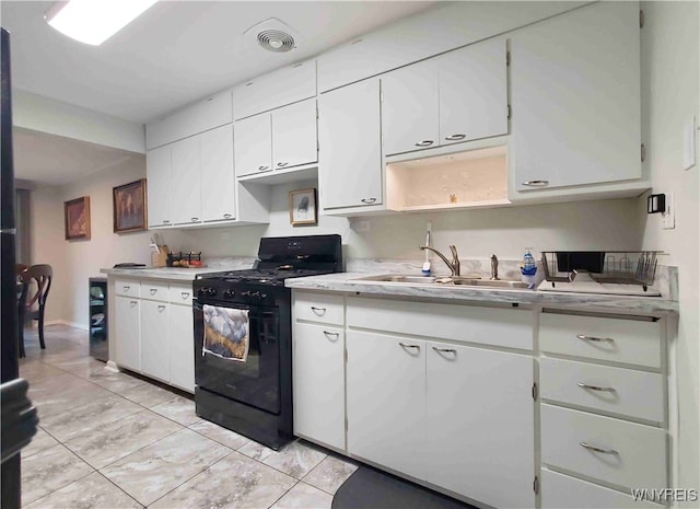 kitchen with gas stove, sink, and white cabinets