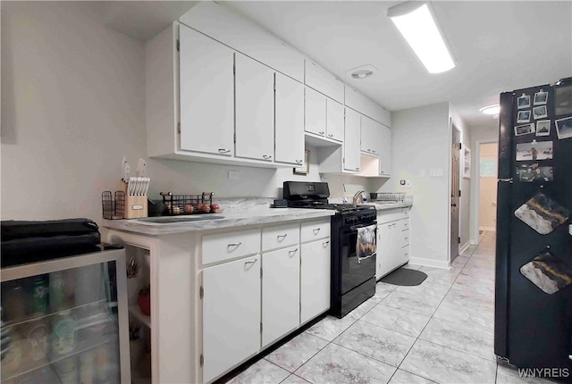 kitchen with black appliances, white cabinetry, and beverage cooler