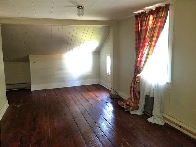 unfurnished room with a baseboard heating unit, vaulted ceiling, dark hardwood / wood-style floors, and wooden walls