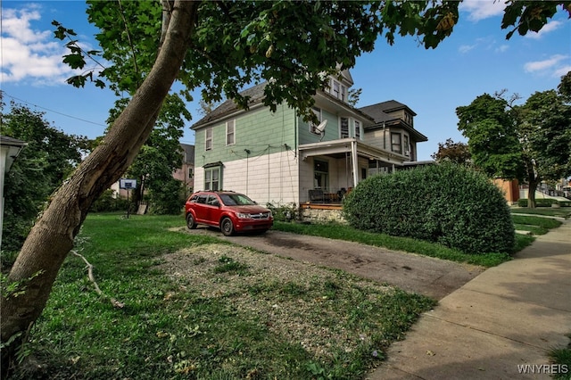 view of side of property with a porch and a yard