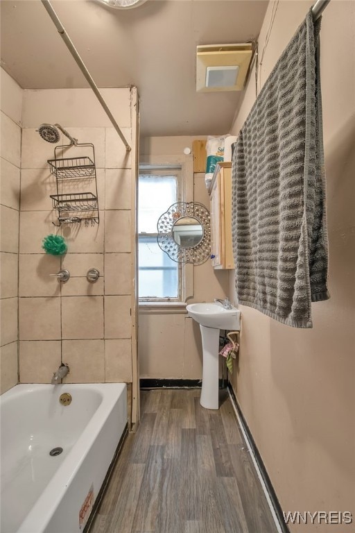 bathroom featuring wood-type flooring, tiled shower / bath, and sink