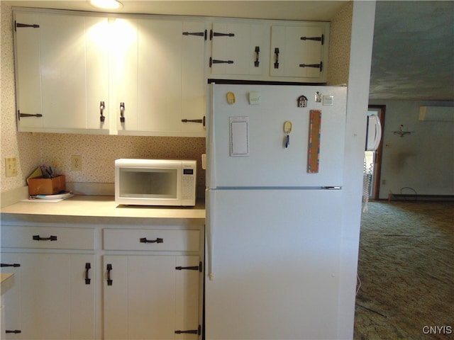 kitchen featuring dark carpet, white appliances, and white cabinets