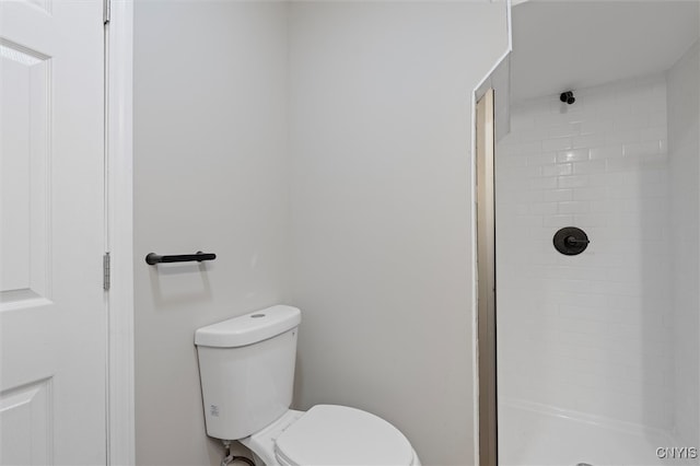 bathroom featuring a tile shower and toilet