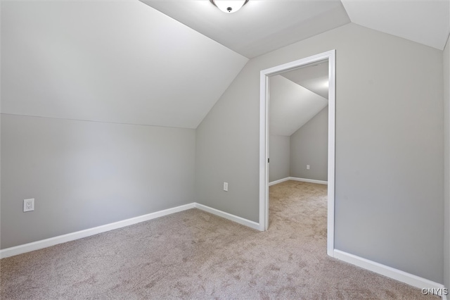 additional living space featuring light colored carpet and vaulted ceiling