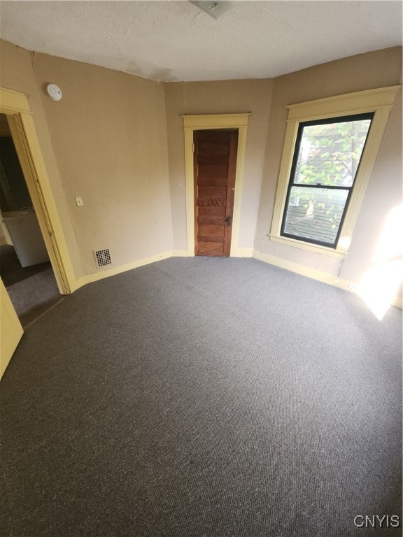 unfurnished room with carpet and a textured ceiling