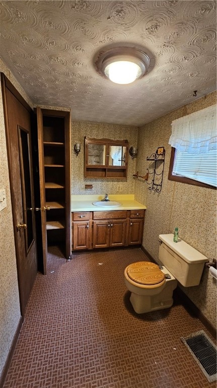 bathroom with a textured ceiling, vanity, and toilet