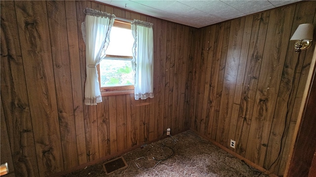 carpeted empty room with wood walls