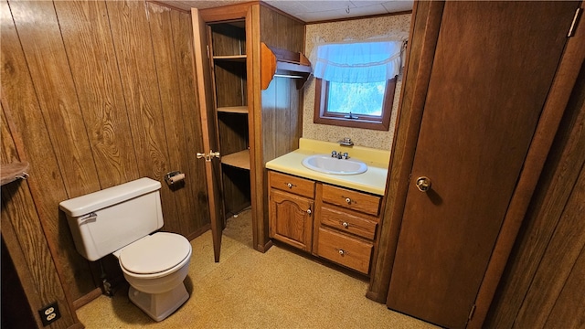 bathroom with vanity, wood walls, and toilet