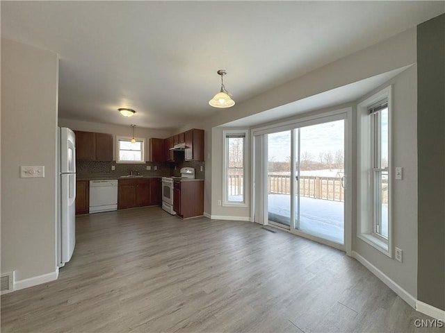 kitchen featuring plenty of natural light, decorative light fixtures, white appliances, and light hardwood / wood-style floors