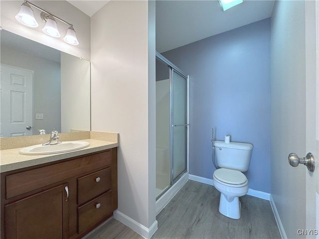 bathroom with hardwood / wood-style floors, vanity, toilet, and a shower with door