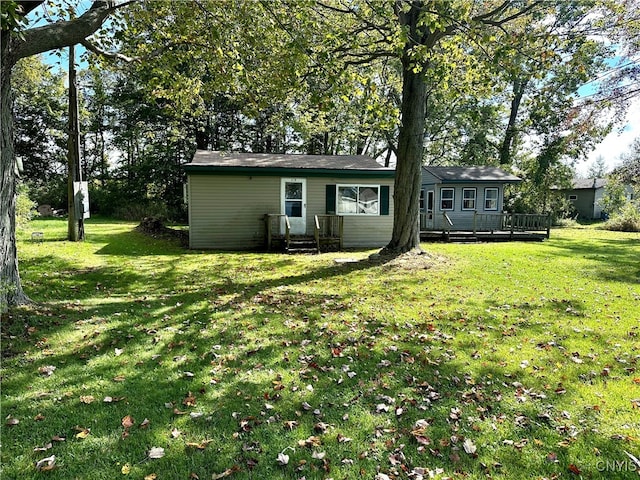 rear view of property featuring a wooden deck and a yard