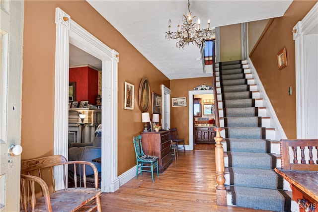 staircase with hardwood / wood-style flooring, a chandelier, and vaulted ceiling