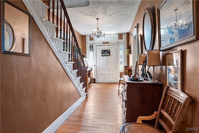 foyer featuring an inviting chandelier, a textured ceiling, and light hardwood / wood-style floors