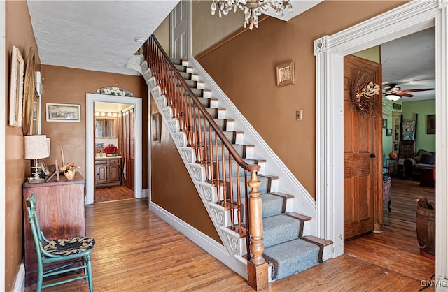 staircase featuring ceiling fan and hardwood / wood-style flooring