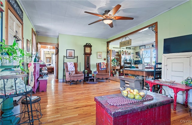 living room with ornamental molding, ceiling fan, and hardwood / wood-style flooring