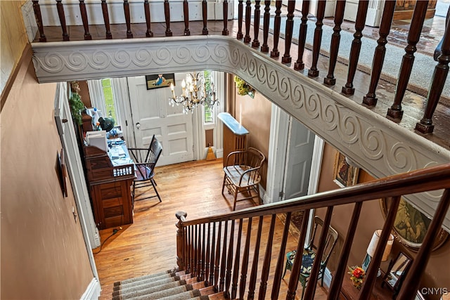 stairs with hardwood / wood-style floors and a chandelier