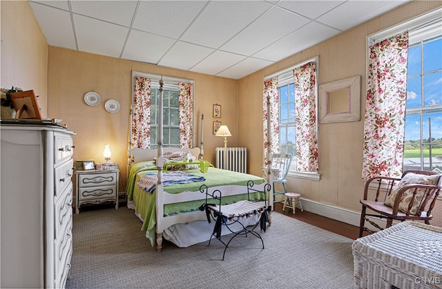 bedroom featuring radiator heating unit, wood-type flooring, and a drop ceiling