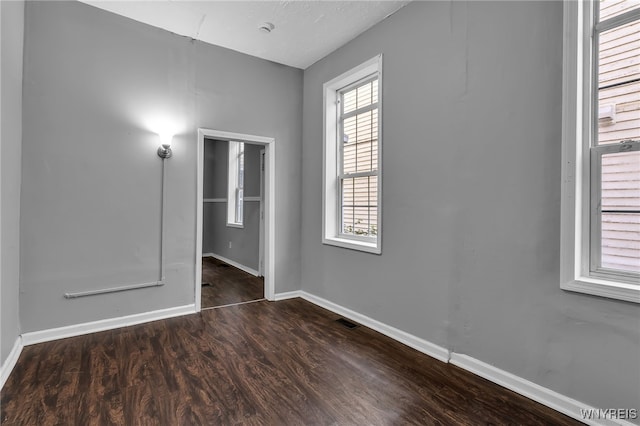 unfurnished room with a healthy amount of sunlight and dark hardwood / wood-style floors