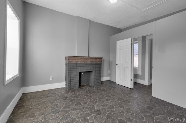 unfurnished living room with a brick fireplace and plenty of natural light