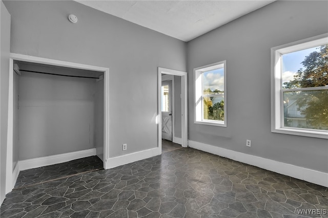 unfurnished bedroom featuring a closet and multiple windows