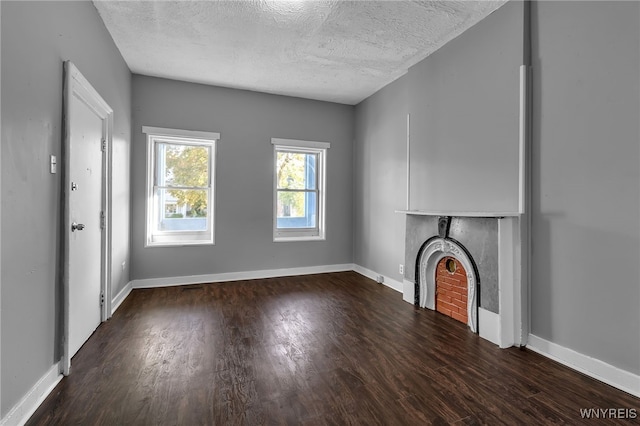 unfurnished living room featuring a textured ceiling and dark hardwood / wood-style flooring