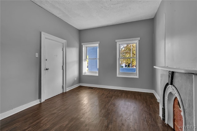 unfurnished living room with a textured ceiling and dark hardwood / wood-style floors