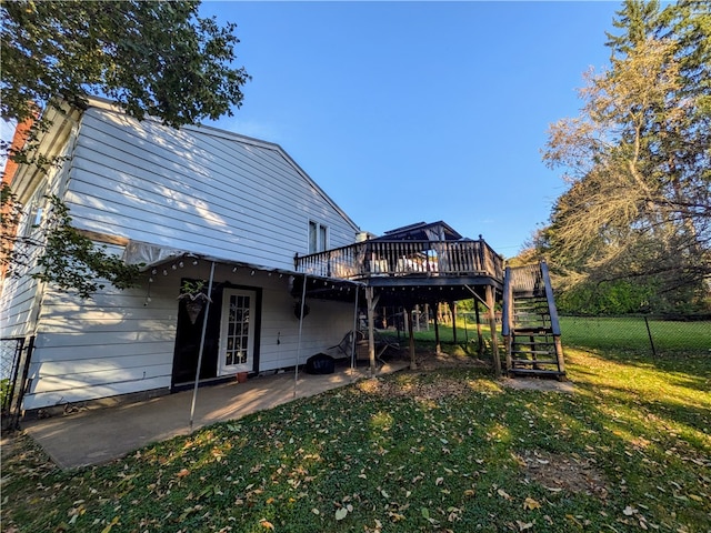 rear view of property featuring a wooden deck, a yard, and a patio