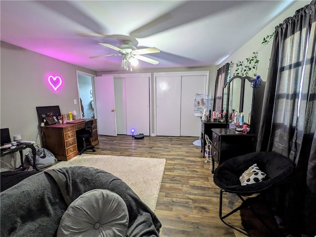 bedroom featuring ceiling fan, two closets, and dark hardwood / wood-style floors