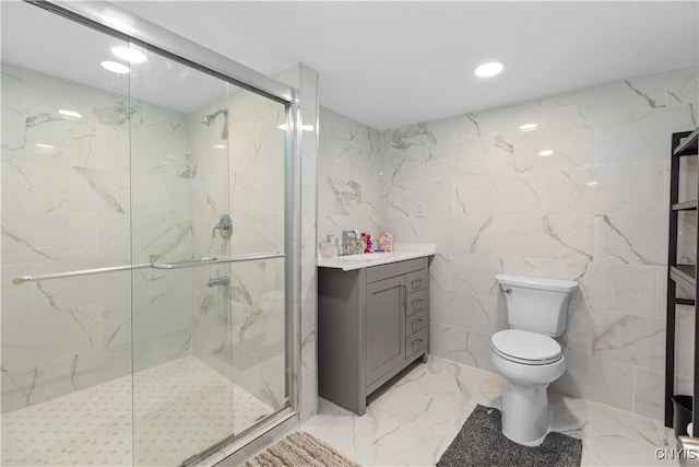 bathroom with tile walls, a shower with door, vanity, and toilet