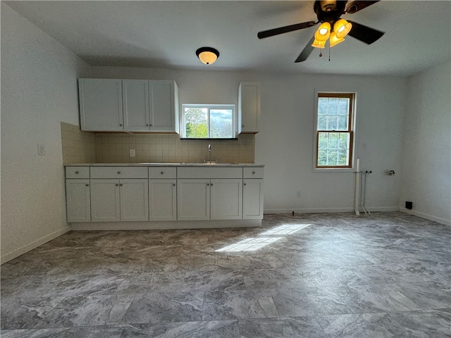 kitchen featuring decorative backsplash, white cabinetry, sink, and a wealth of natural light