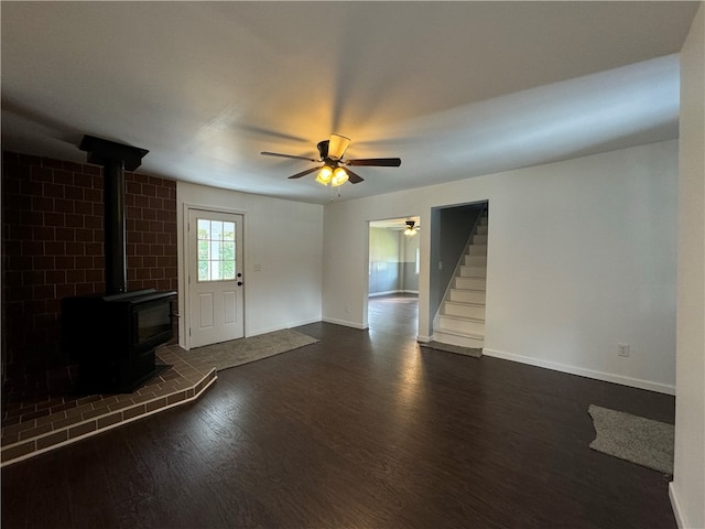 unfurnished living room with dark hardwood / wood-style floors, ceiling fan, and a wood stove