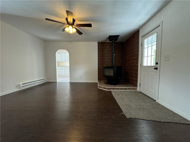 unfurnished living room featuring a wood stove, ceiling fan, baseboard heating, and dark hardwood / wood-style floors