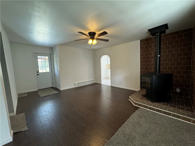 unfurnished living room with a wood stove, ceiling fan, baseboard heating, and dark hardwood / wood-style floors