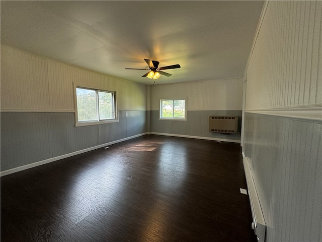 spare room with ceiling fan, heating unit, and dark hardwood / wood-style floors