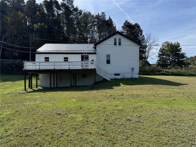 rear view of house featuring a wooden deck and a yard