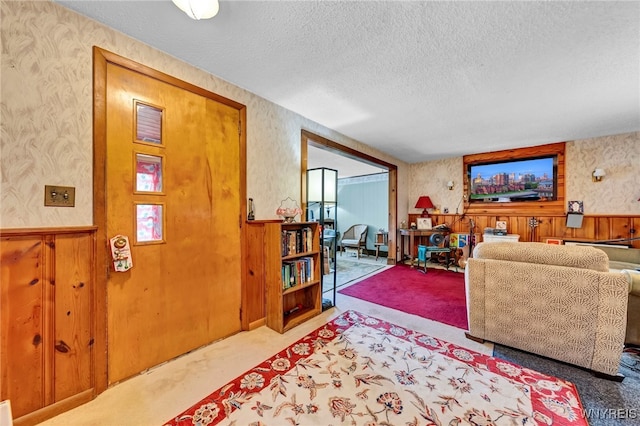 living room featuring carpet, wooden walls, and a textured ceiling