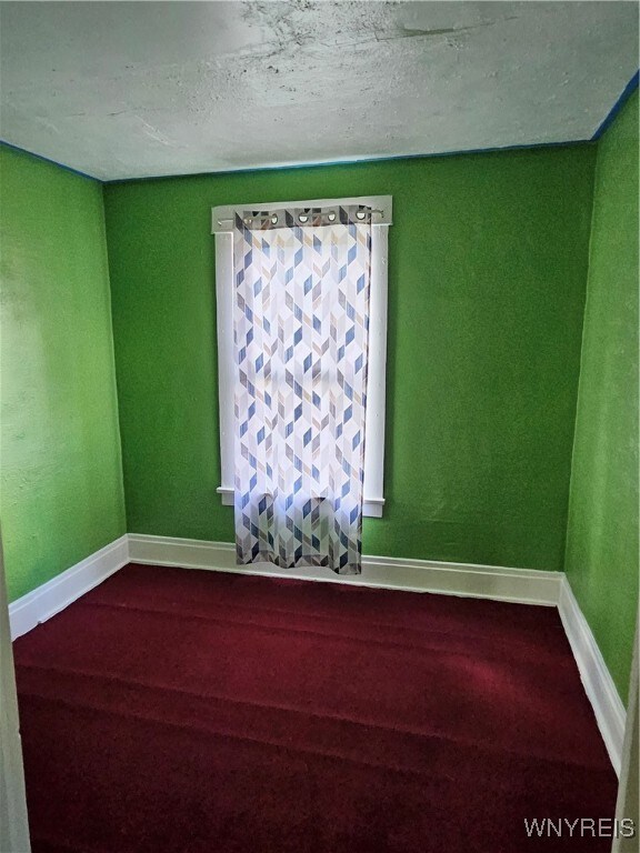 carpeted spare room featuring a textured ceiling