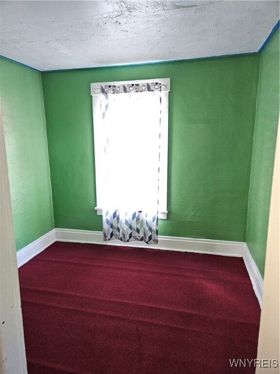 carpeted spare room with a textured ceiling